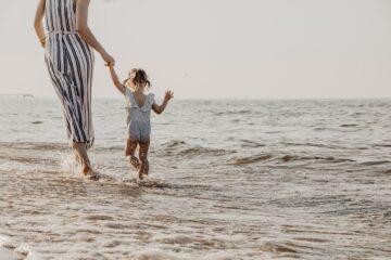 woman and child walking on beach